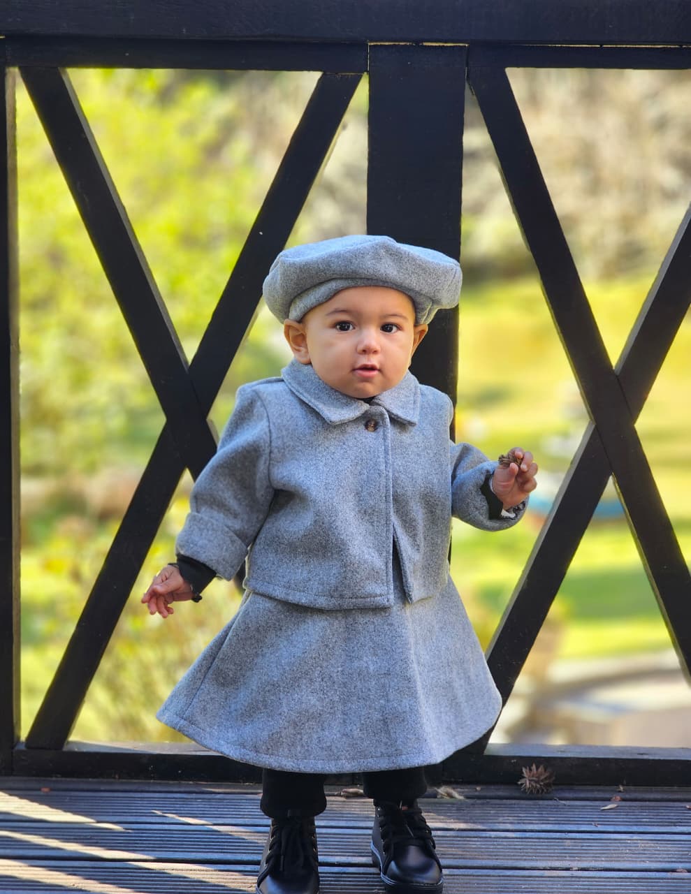 Liz Sofia com casaco cinza em frente ao jardim